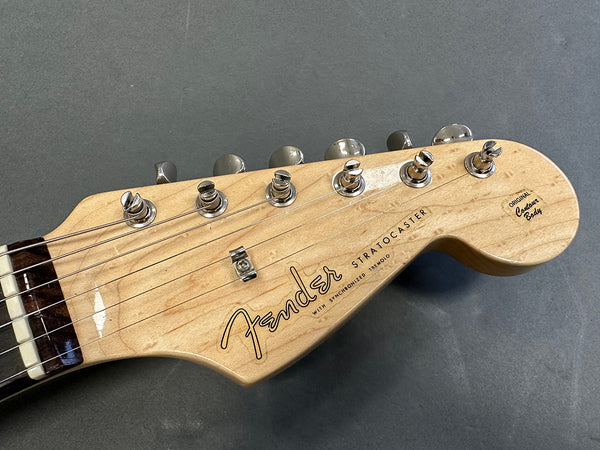 Close-up of Fender Stratocaster natural wood guitar headstock with tuning pegs and logo on gray background