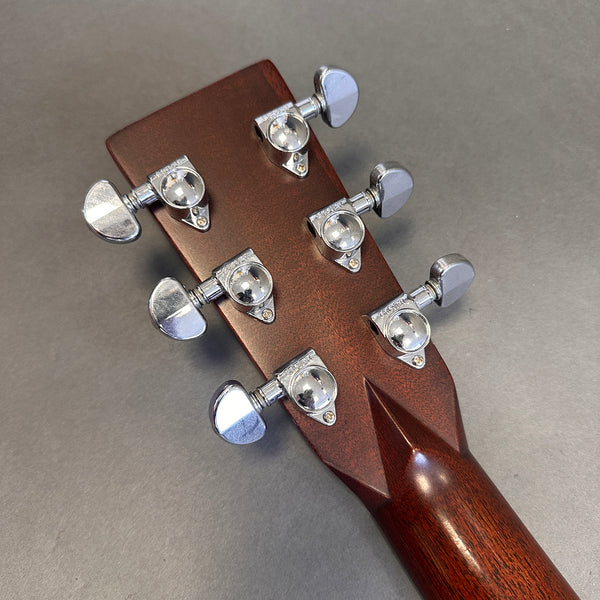 Close-up of guitar headstock back showing chrome Grover tuning pegs on mahogany wood neck against gray background