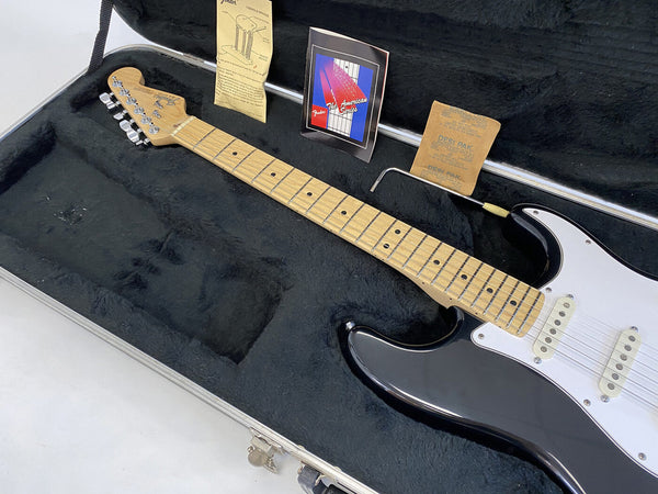 Fender American Series black electric guitar with maple neck and white pickguard inside hard case with tremolo arm and Fender manuals