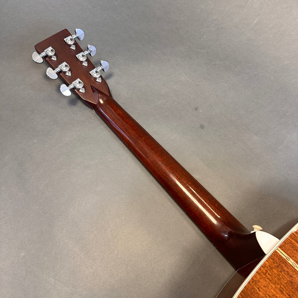 Back view of acoustic guitar neck and headstock with chrome tuning pegs on gray background