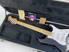 Fender American Series electric guitar in black with maple neck and white pickguard in black plush-lined hard case with tremolo arm and Fender documentation.