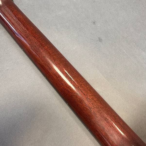 Close-up of polished mahogany guitar neck showing wood grain texture on gray surface background