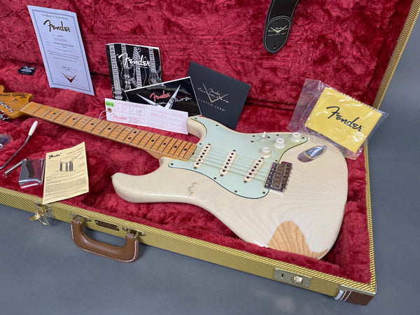 Fender Vintage Stratocaster electric guitar in white with maple neck and aged finish, displayed in a red velvet hard case with original Fender certificate of authenticity, care booklet, tremolo arm, and Fender branded strap and cleaning cloth.