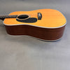 Acoustic dreadnought guitar with natural spruce top and dark wood sides and back on gray background