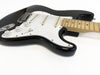 Black electric guitar with white pickguard and maple neck on white background, close-up of body and controls