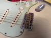 Close-up of vintage electric guitar bridge, pickups, and volume and tone control knobs on cream-colored body with aged pickguard