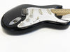 Black electric guitar with white pickguard and maple neck, three single-coil pickups, volume and tone control knobs, photographed on white background