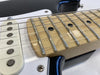 Close-up of electric guitar maple fretboard with metal frets and black dot inlays, white single-coil pickup, and black guitar bodyedges