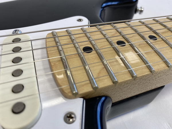 Close-up of electric guitar maple fretboard with metal frets and black dot inlays, white single-coil pickup, and black guitar bodyedges