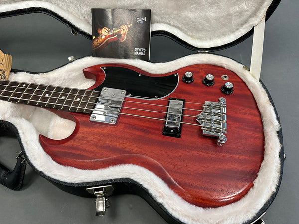 Gibson electric bass guitar in cherry wood finish with chrome hardware, black pickguard, and control knobs inside plush white-lined guitar case with Gibson owner's manual