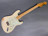 Vintage Fender Stratocaster electric guitar with maple neck, aged white finish, and three single-coil pickups on gray background