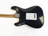 Black Fender electric guitar back view with maple neck and white tremolo cavity cover plate on white background