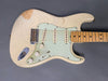 Vintage white electric guitar with distressed finish, maple neck, three single-coil pickups, and white pickguard on gray background