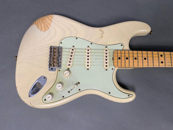 Vintage white electric guitar with distressed finish, maple neck, three single-coil pickups, and white pickguard on gray background