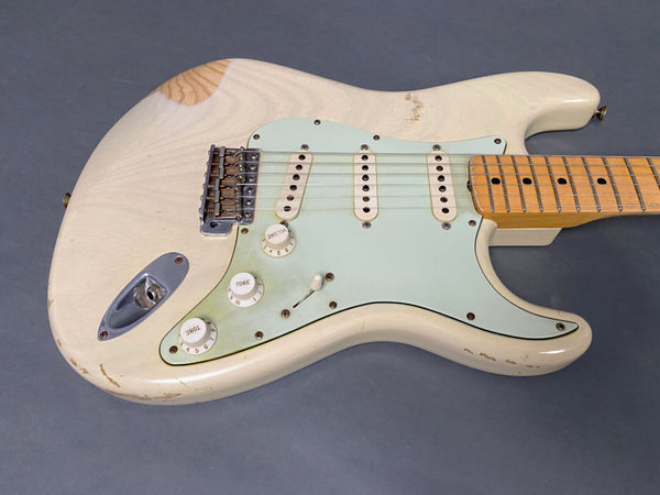 Vintage white electric guitar with maple neck, three single-coil pickups, and white control knobs on a grey background