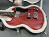 Cherry red electric bass guitar with black pickguard and chrome hardware in a white fur-lined hard case with owner's manual