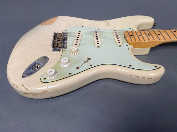 Vintage white electric guitar with three single-coil pickups, maple neck, and aged finish showing wear and scratches on body