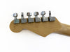 Close-up of natural wood guitar headstock with six chrome tuning pegs on a white background