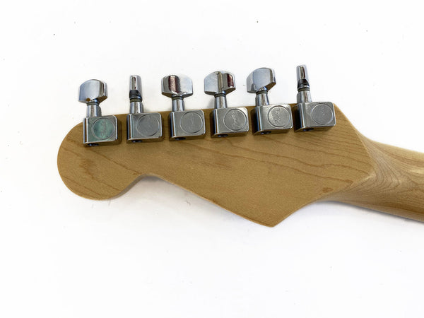 Close-up of natural wood guitar headstock with six chrome tuning pegs on a white background