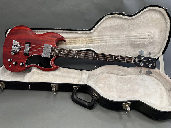 Gibson SG-style electric bass guitar in cherry red finish with black pickguard in open black hardshell guitar case with plush white interior lining