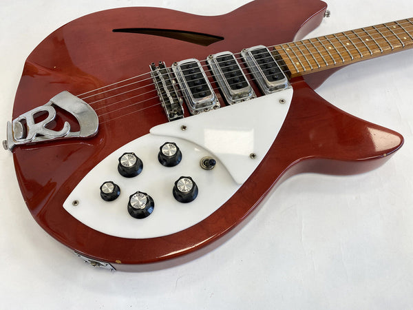 Vintage red electric guitar with white pickguard and multiple tone and volume knobs on white background