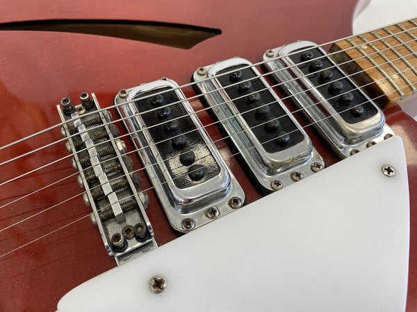Close-up of vintage electric guitar pickups and bridge on red hollow body guitar with white pickguard