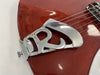 Close-up of vintage Rickenbacker guitar tailpiece on red electric guitar body with strings and metal hardware