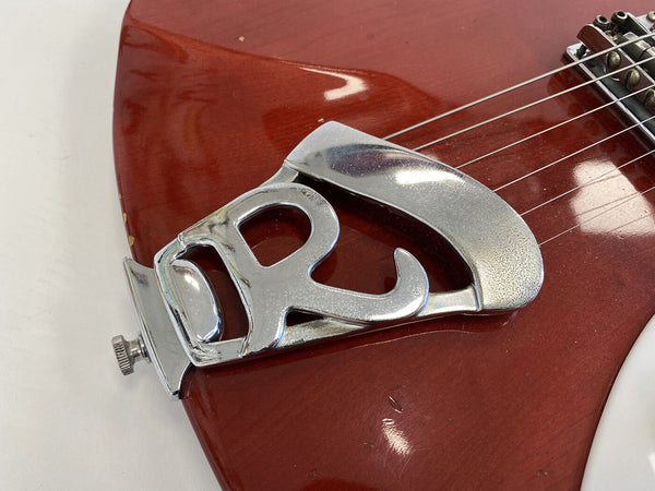 Close-up of vintage Rickenbacker guitar tailpiece on red electric guitar body with strings and metal hardware