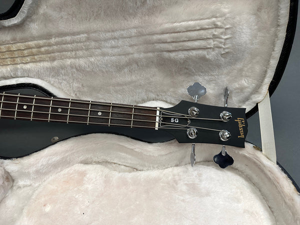 Close-up of Gibson SG bass guitar headstock and fretboard inside plush lined guitar case