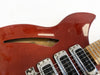 Close-up of red semi-hollow electric guitar body with three chrome and black pickups and f-hole on top side