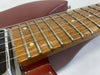 Close-up of electric guitar fretboard with metal frets, dot inlays, and steel strings on red body finish