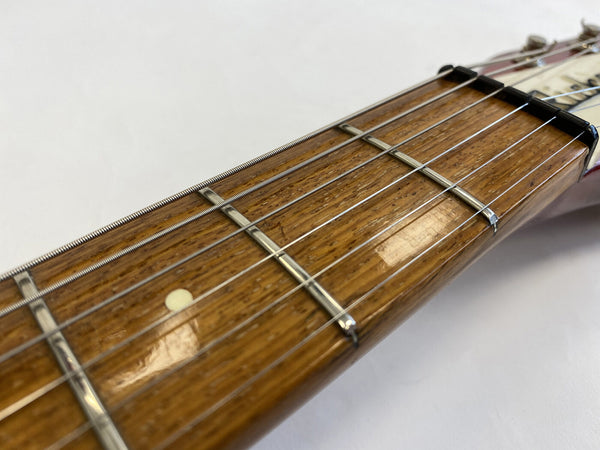 Close-up of guitar neck and fretboard showing metal frets, steel guitar strings, and wood grain finish on acoustic guitar fingerboard