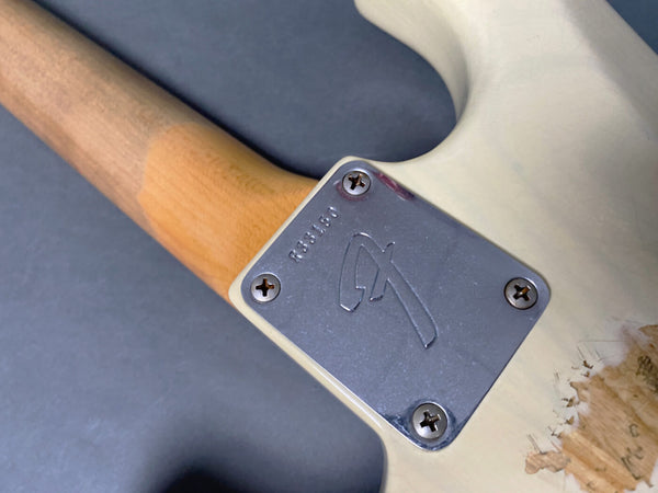 Close-up of Fender guitar neck plate with serial number and natural wood neck on worn white guitar body