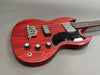 Red electric bass guitar with black pickguard and chrome hardware on gray background
