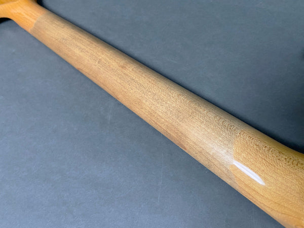 Close-up of natural wood guitar neck with smooth finish on gray background