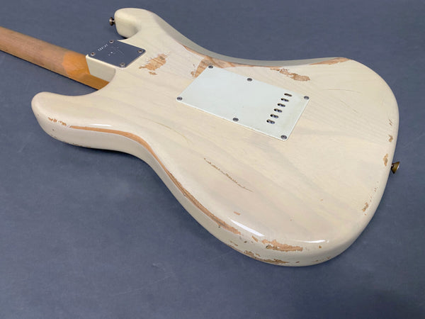 Rear view of worn vintage white electric guitar body with visible wood and paint chips against dark background