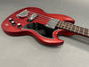 Cherry red electric bass guitar with black pickguard, chrome pickups, and control knobs on gray background