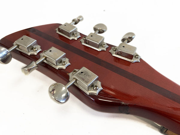 Close-up of vintage guitar headstock with six metal tuning pegs and dark wood stripe on red-brown finish background