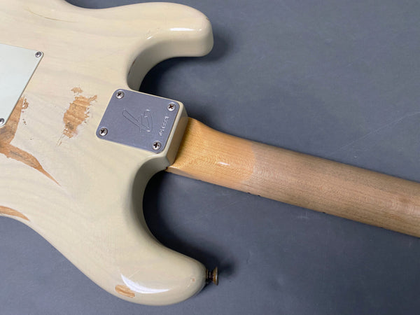 Vintage cream electric guitar body with worn finish and maple neck on grey background, showing metal neck plate with screws