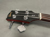 Close-up image of Gibson bass guitar headstock with chrome tuning pegs and strings on gray background