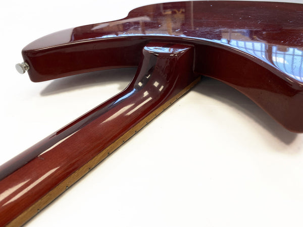 Close-up view of the neck joint and heel of a glossy dark red electric guitar body on white background