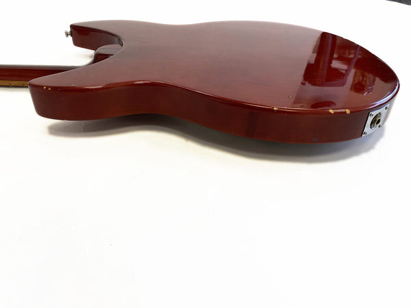 Cherry red electric guitar body showing side profile with visible wear and chips near input jack, on white background