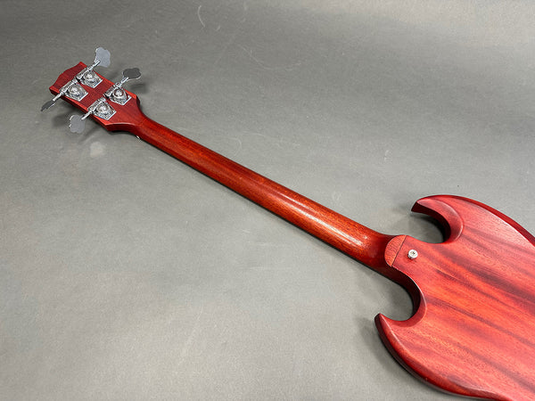 Back view of red electric bass guitar neck and body on gray background