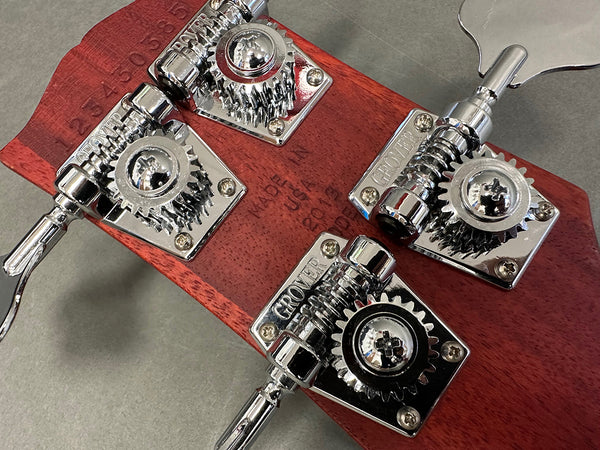 Close-up of Grover tuning machines on the back of a mahogany guitar headstock with serial number and "Made in USA" stamp visible