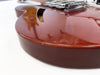 Close-up of cherry red semi-hollow electric guitar body edge showing minor paint chip and glossy finish