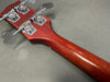 Close-up of bass guitar headstock back showing chrome tuning pegs and reddish-brown wooden neck