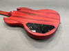 Back view of red electric guitar body showing wood grain texture and black plastic control cavity cover on gray background