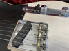 Close-up of vintage Fender guitar bridge and pickup with chrome control knobs on white cracked finish guitar body