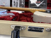 Close-up of Fender guitar case handle and badge with a vintage white Fender electric guitar neck and body resting inside a red plush interior.