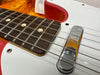 Close-up of electric guitar bridge, strings, and rosewood fretboard with dot inlays on white pickguard and red sunburst body finish